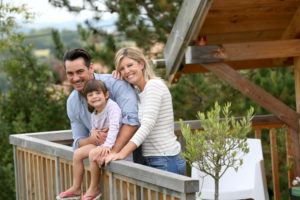 A happy family on the deck of their log cabin.